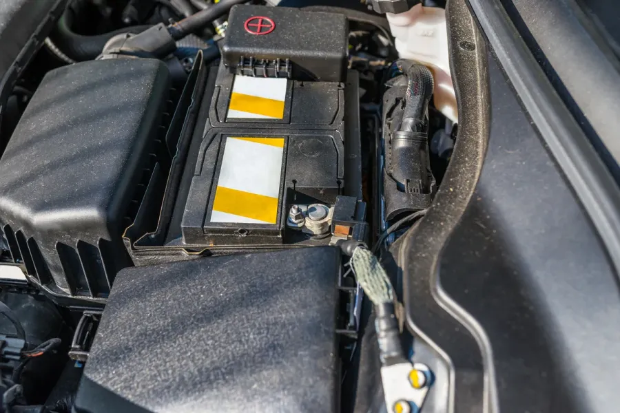 Starterbatterie im Motorraum mit abgedeckten Polen und umliegenden Kabeln