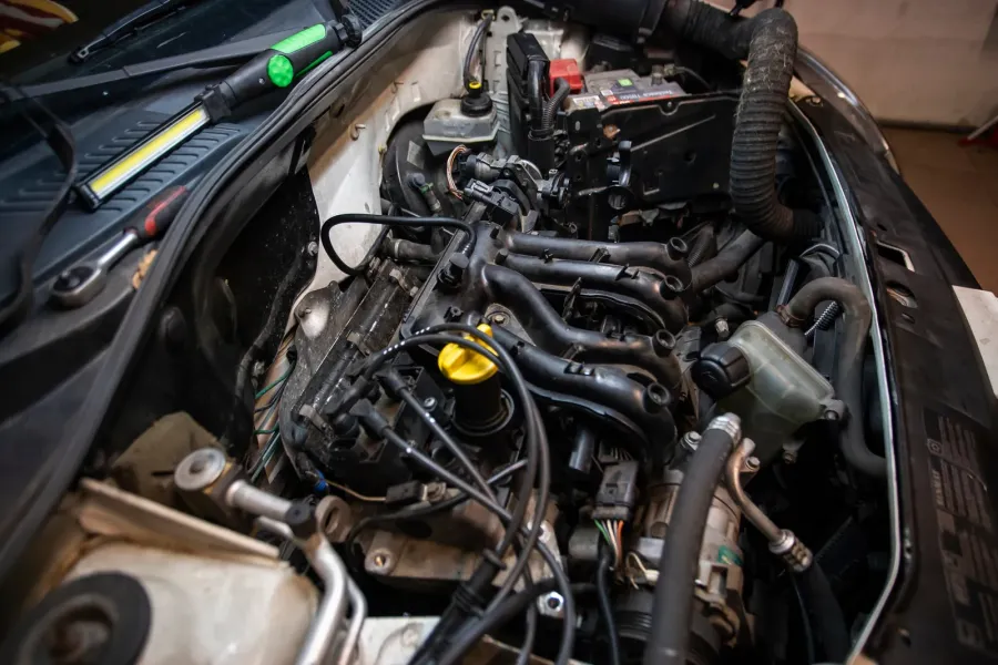 Verschmutzter Motorraum mit Staubfilm auf Leitungen und Abdeckungen bei geöffneter Motorhaube