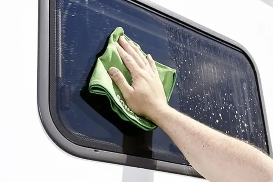 Acrylglas-Fenster eines Wohnwagens wird mit viel Wasser und einem weichen Tuch gereinigt