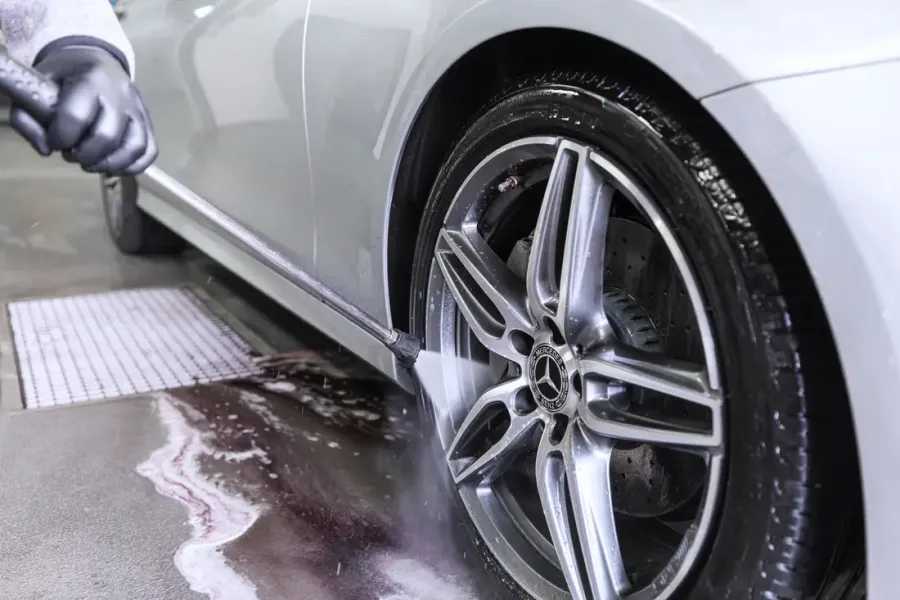 Rad eines silbernen Mercedes wird mit dem Hochdruckreiniger abgespült
