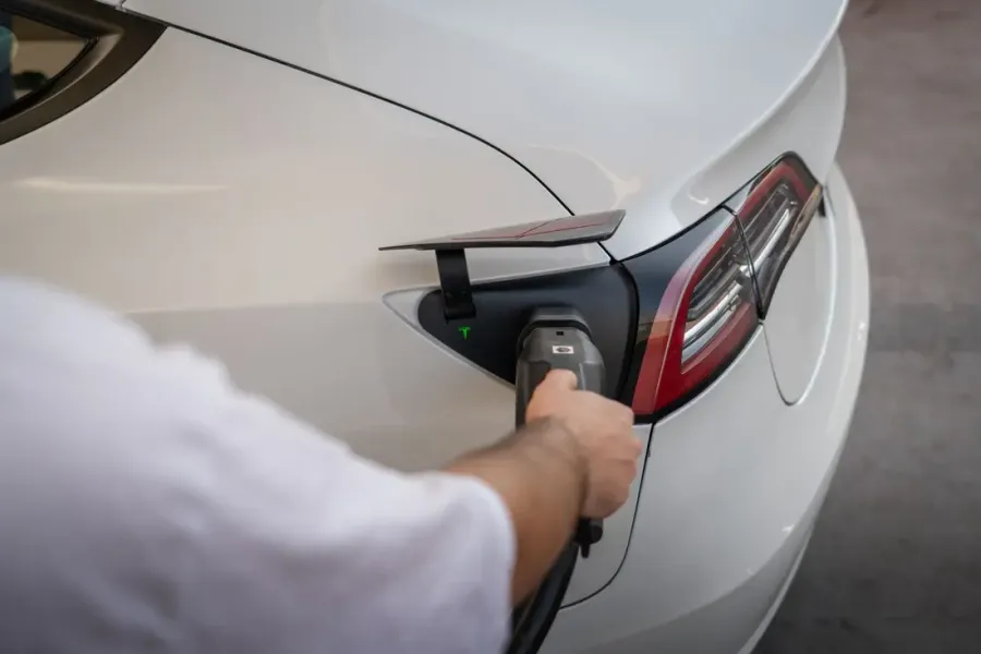 Ladestecker wird in den Ladeanschluss eines weißen Elektroautos gesteckt