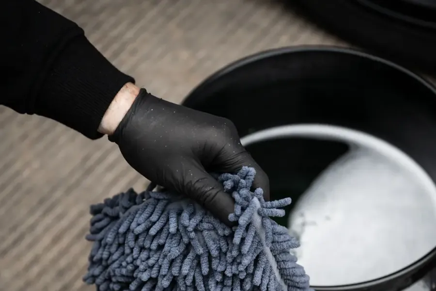 Waschhandschuh wird aus einem Eimer mit Schmutzeinsatz genommen