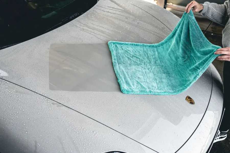 Motorhaube wird mit einem großen Mikrofaser-Trockentuch abgezogen