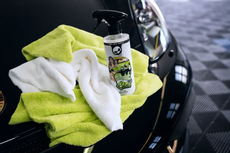Mikrofasertücher und Sprühflasche auf einer schwarzen Motorhaube